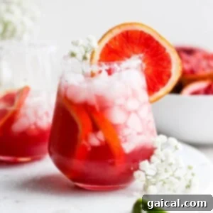 Two glasses of grapefruit margarita adorned with ice and flowers, showcasing a vibrant citrus cocktail.