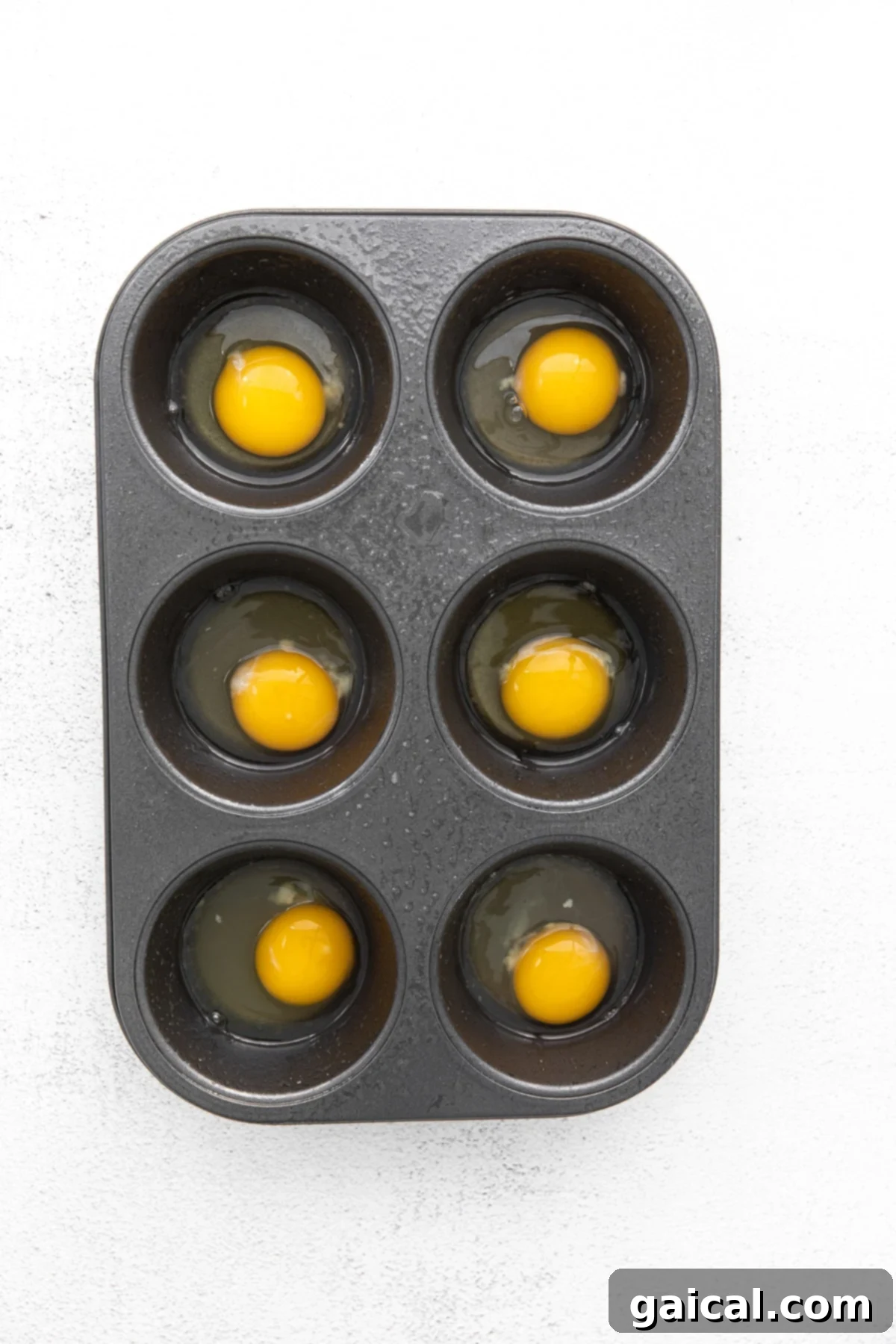 Preparing raw eggs in a muffin tin for baking. raw eggs in muffin tin ready for baking