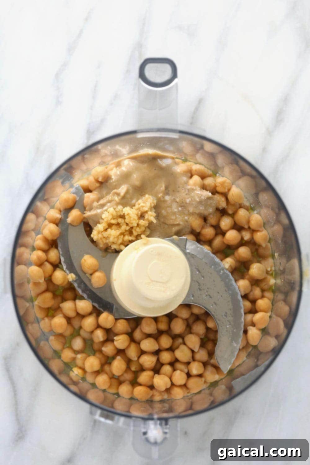 Creamy Homemade Hummus Made Easy 3 All the ingredients for lemon garlic hummus arranged in a food processor, ready to be blended.