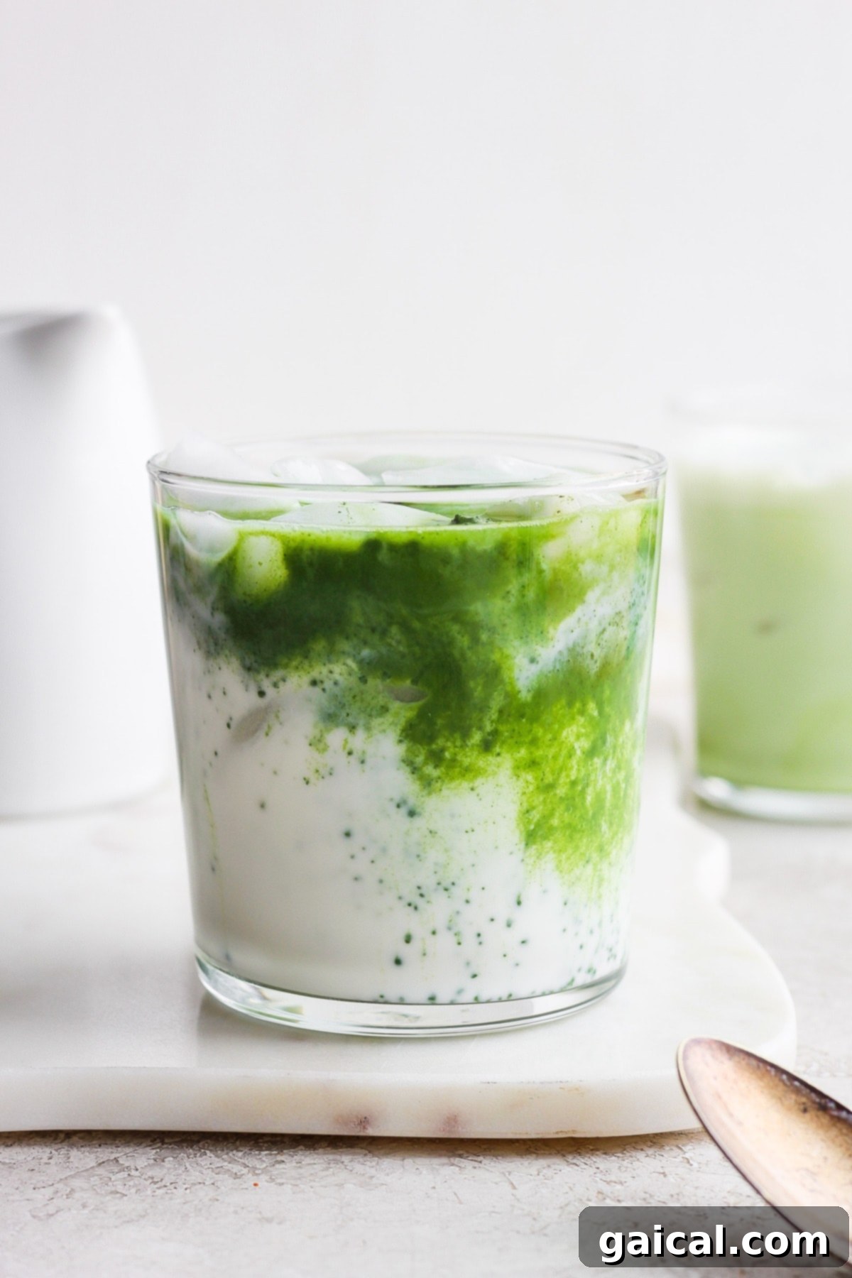 A vibrant iced latte with a distinct matcha swirl blending into almond milk, ready to be enjoyed.