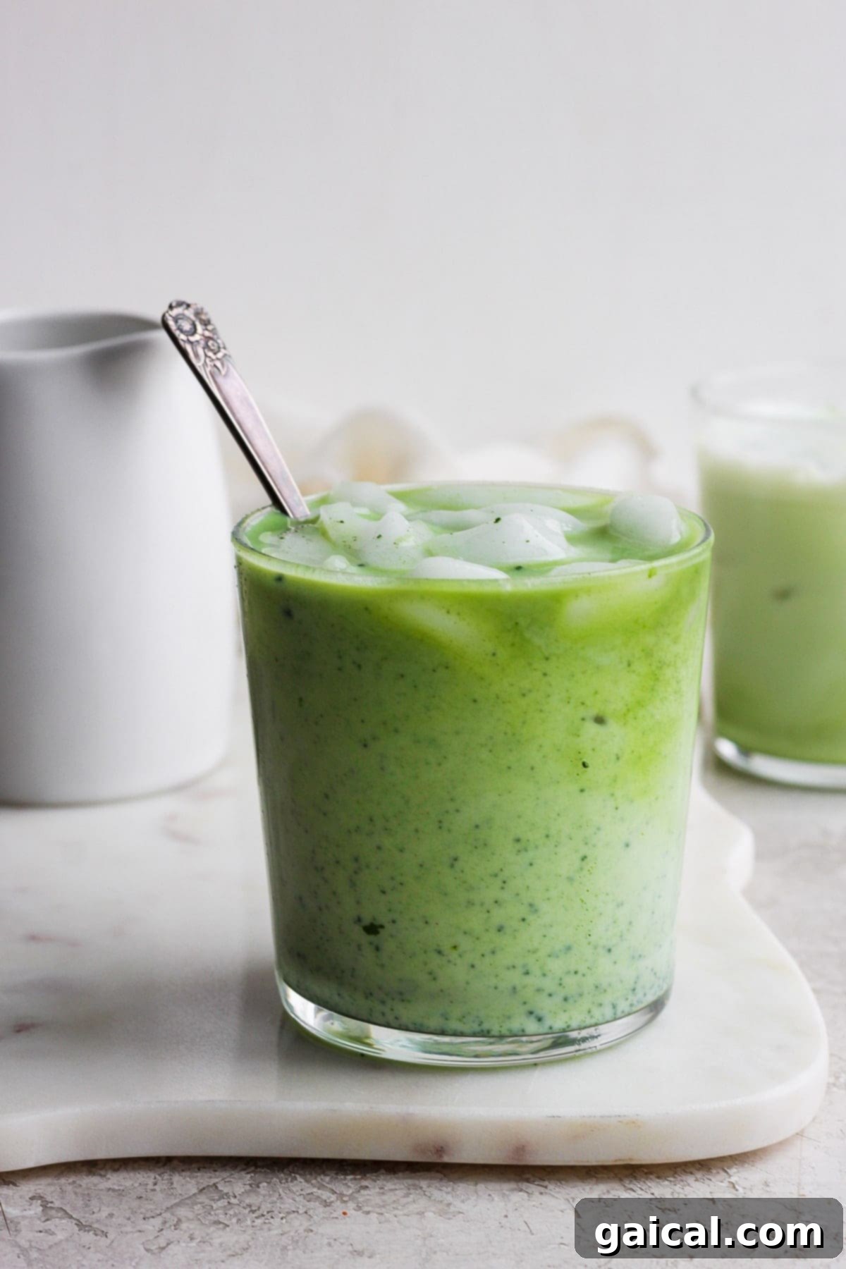 A glass of iced matcha latte sitting on a rustic wooden surface, ready to be enjoyed.