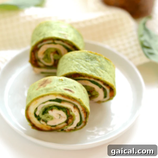 Simple Turkey Pinwheels 2 Three spinach and chicken wraps on a plate.