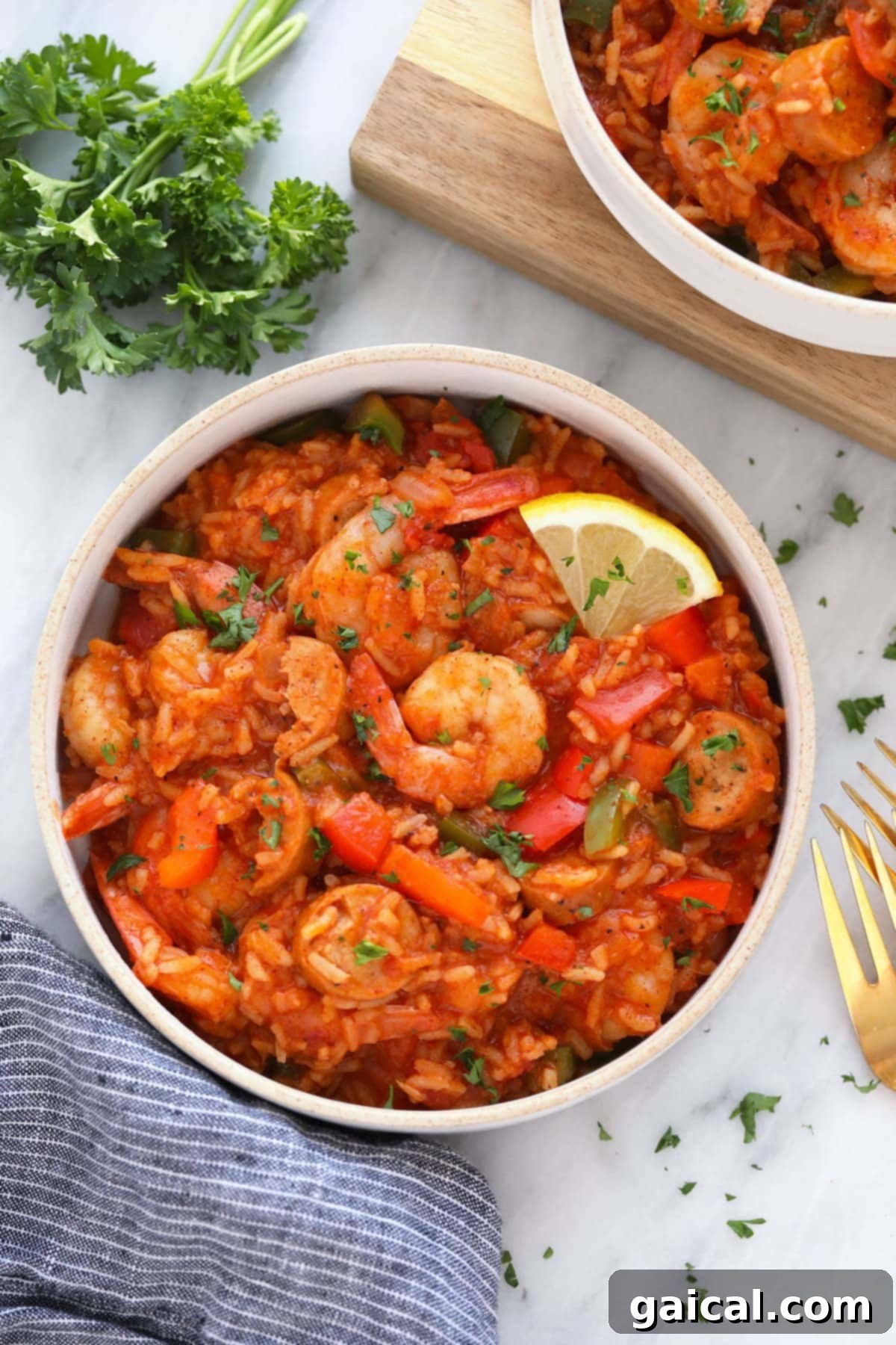 Easy Instant Pot Jambalaya 2 A steaming bowl of Instant Pot Jambalaya garnished with fresh parsley and a lemon slice, ready to be enjoyed, showcasing the rich colors of rice, shrimp, and sausage.
