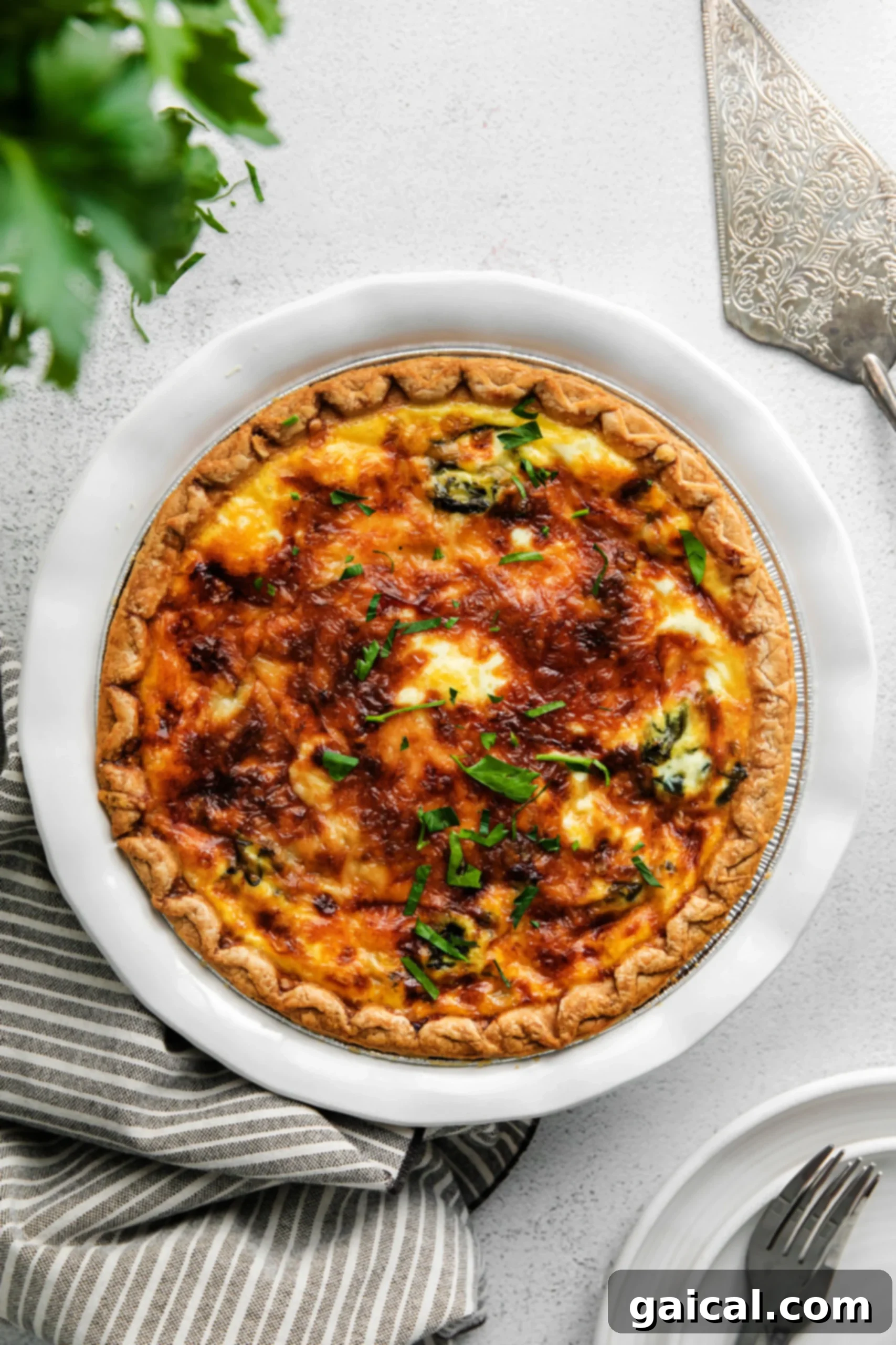 Simple & Savory Spinach Quiche 8 A beautifully baked spinach quiche, its golden-brown top sprinkled with fresh parsley for garnish. The texture suggests a perfectly set and creamy filling within a flaky crust, indicating a delightful meal.