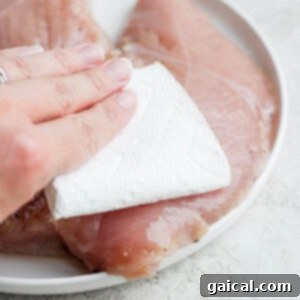 hand patting turkey tenderloin on plate.