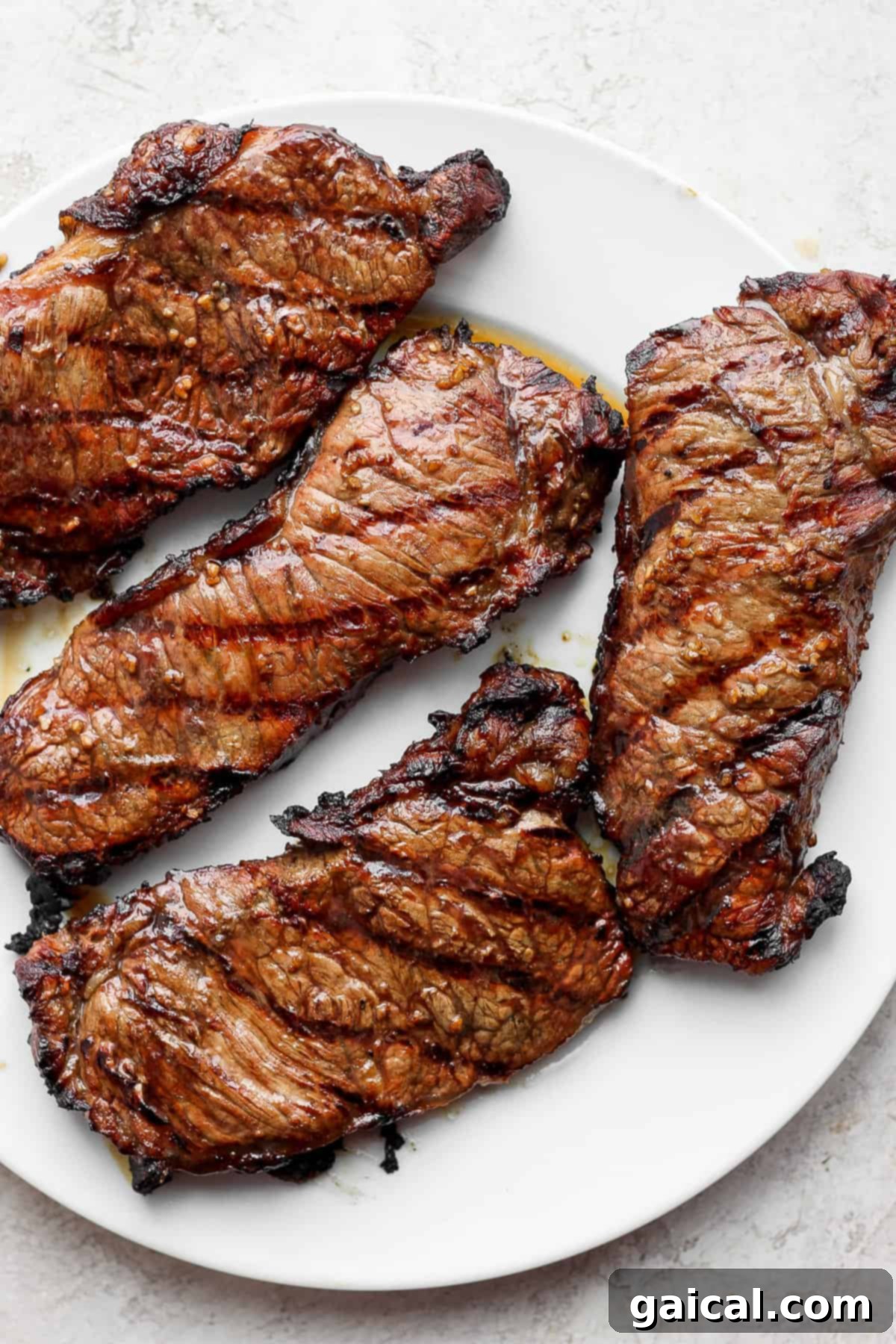 Four large, perfectly grilled steaks on a platter, ready to be served.