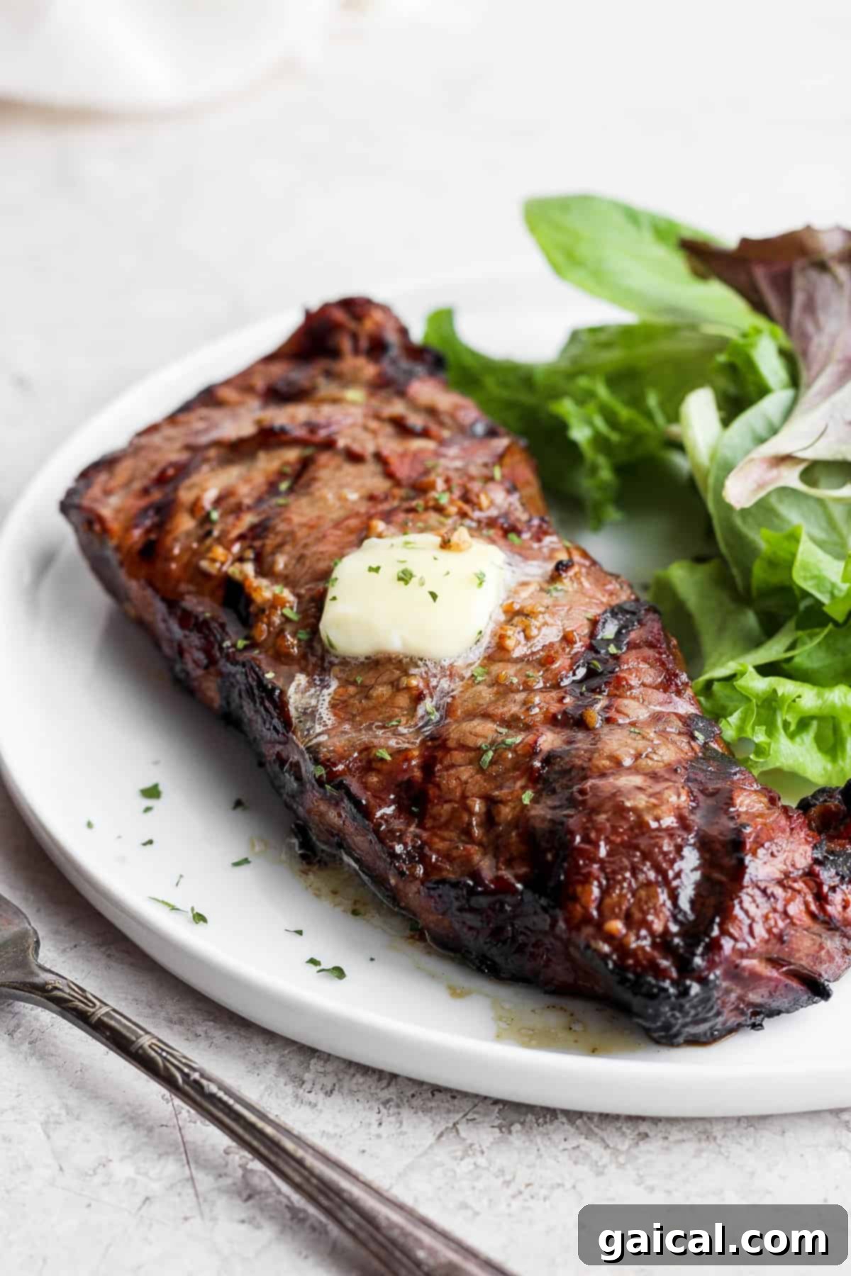 Grilled steak sliced, served with a fresh green salad on a plate.