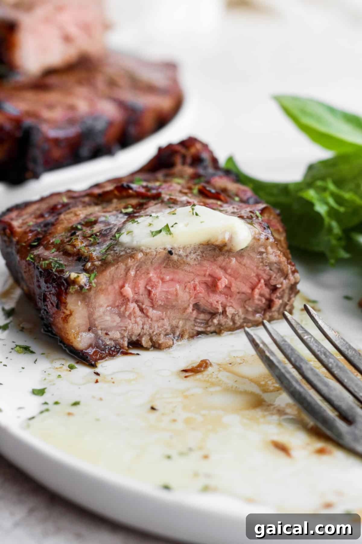 Sliced grilled steak with a pat of butter melting, showcasing its juiciness.