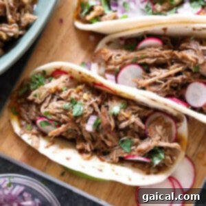 Perfect Homemade Carnitas 9 Tender carnitas on a cutting board with fresh cilantro and lime wedges.