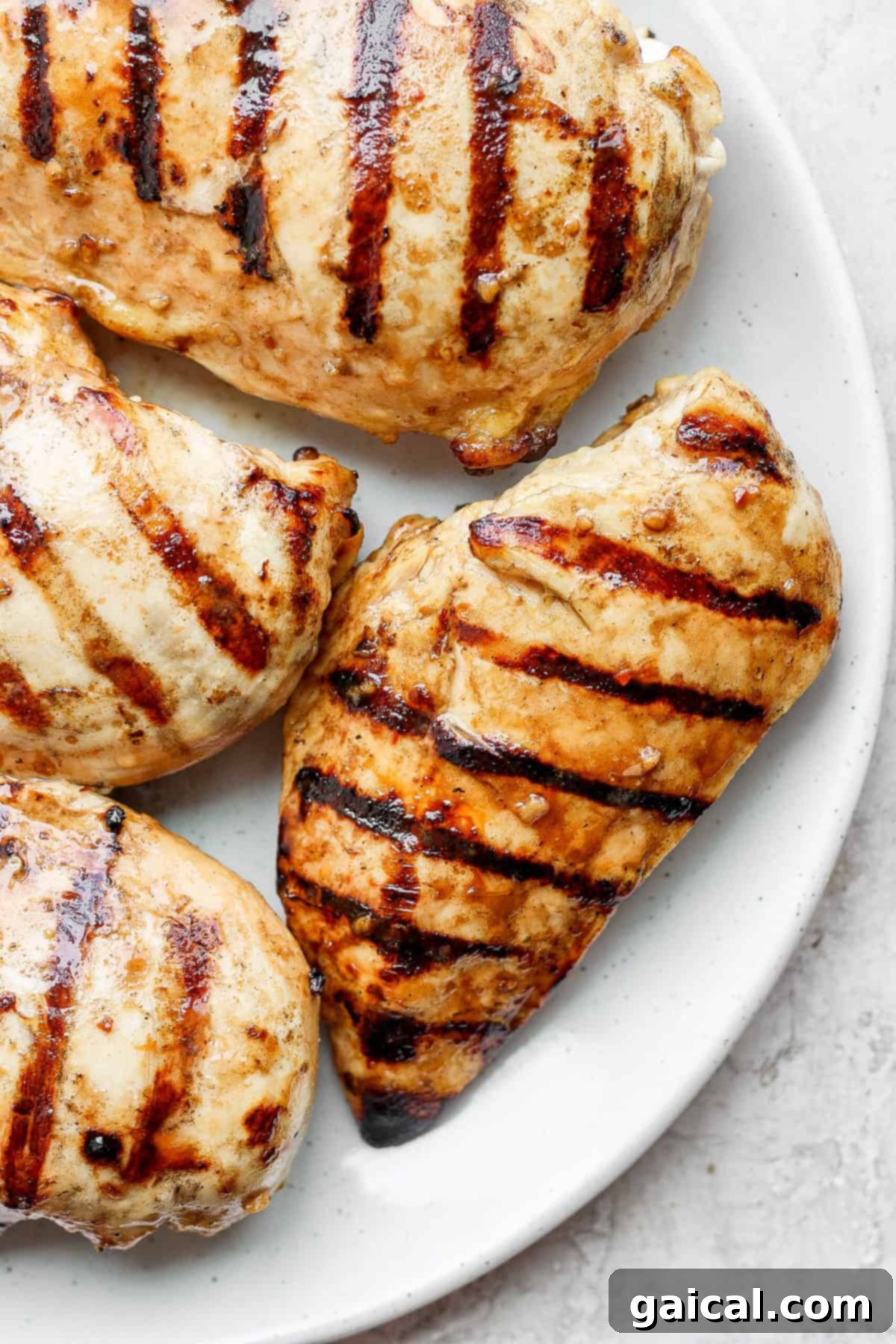 The Best Grilled Chicken Marinade: Delivering Unrivaled Flavor and Juiciness for Your Next Meal. Perfectly grilled chicken breasts served on a pristine white plate, garnished lightly, showcasing a beautiful golden-brown char and succulent texture, ready to be enjoyed.