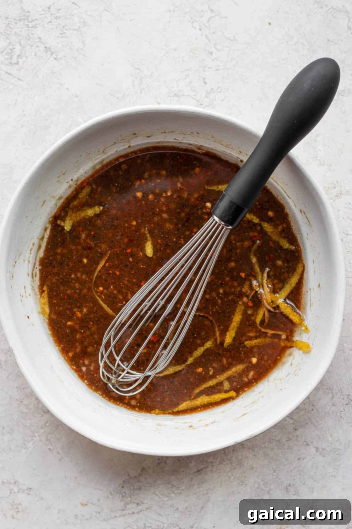 The ultimate homemade grilled chicken marinade, perfectly mixed and ready to infuse flavor. A bowl filled with a rich, dark grilled chicken marinade, prominently featuring fresh herbs and garlic, signifying its readiness for use.