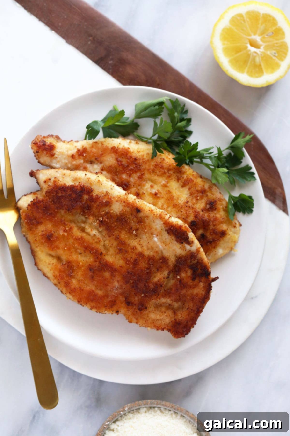 Two cooked chicken breasts resting on a white plate, ready for serving or storage.
