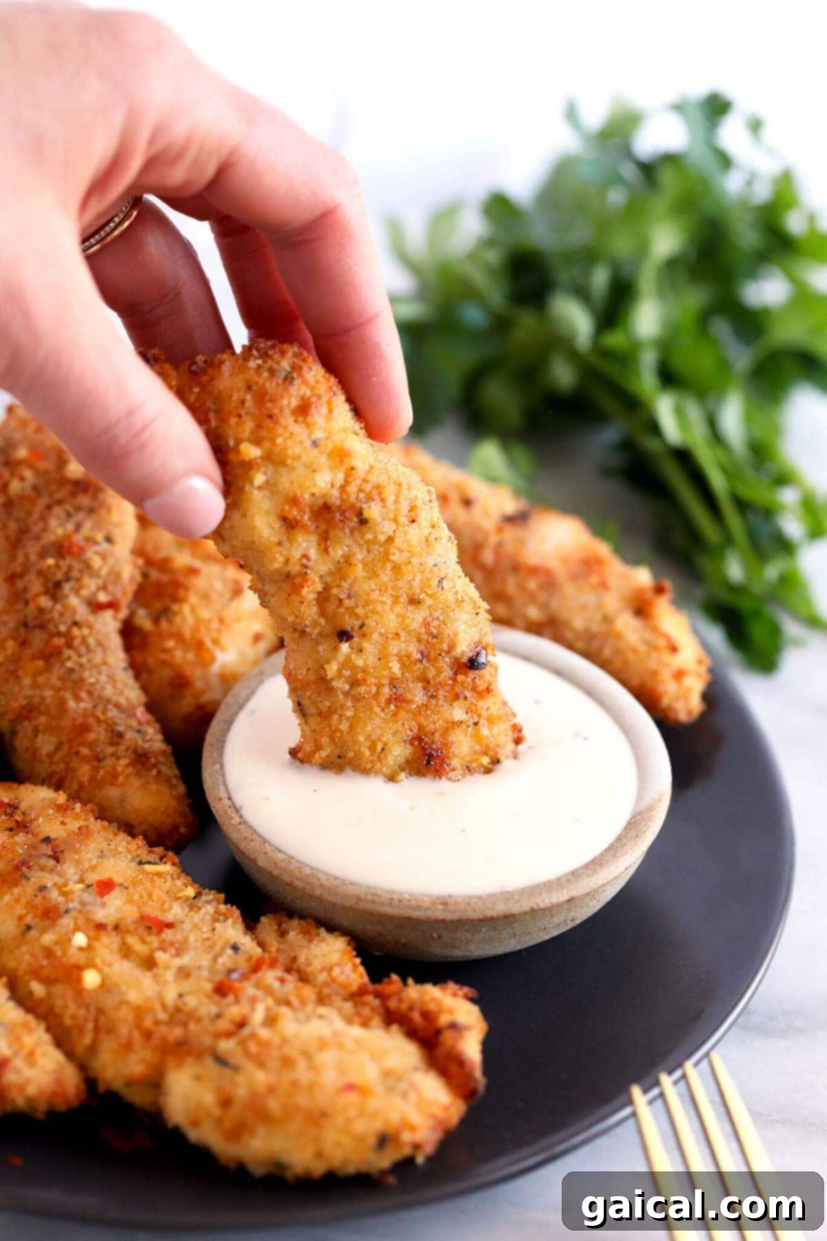 The most crispy on the outside and tender on the inside Air Fryer Chicken Tenders! These chicken tenders (air fryer style) are so easy to make, high protein, and kid-friendly. dipping chicken tender in ranch