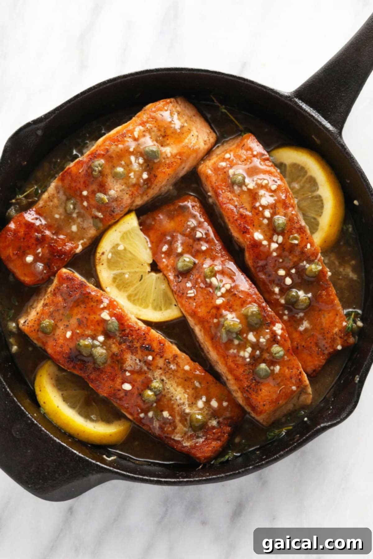 Crispy Salmon Piccata served in a rustic cast iron skillet with lemon slices and fresh capers.