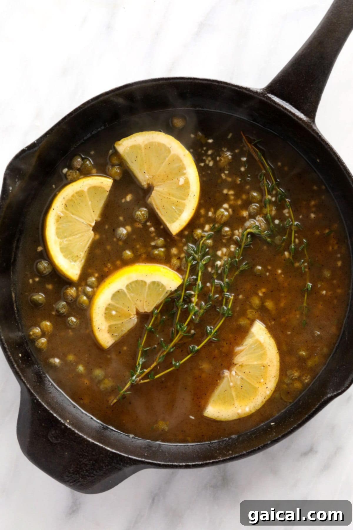 A close-up of the rich and creamy piccata sauce with fresh lemon slices, vibrant capers, and aromatic thyme sprigs.