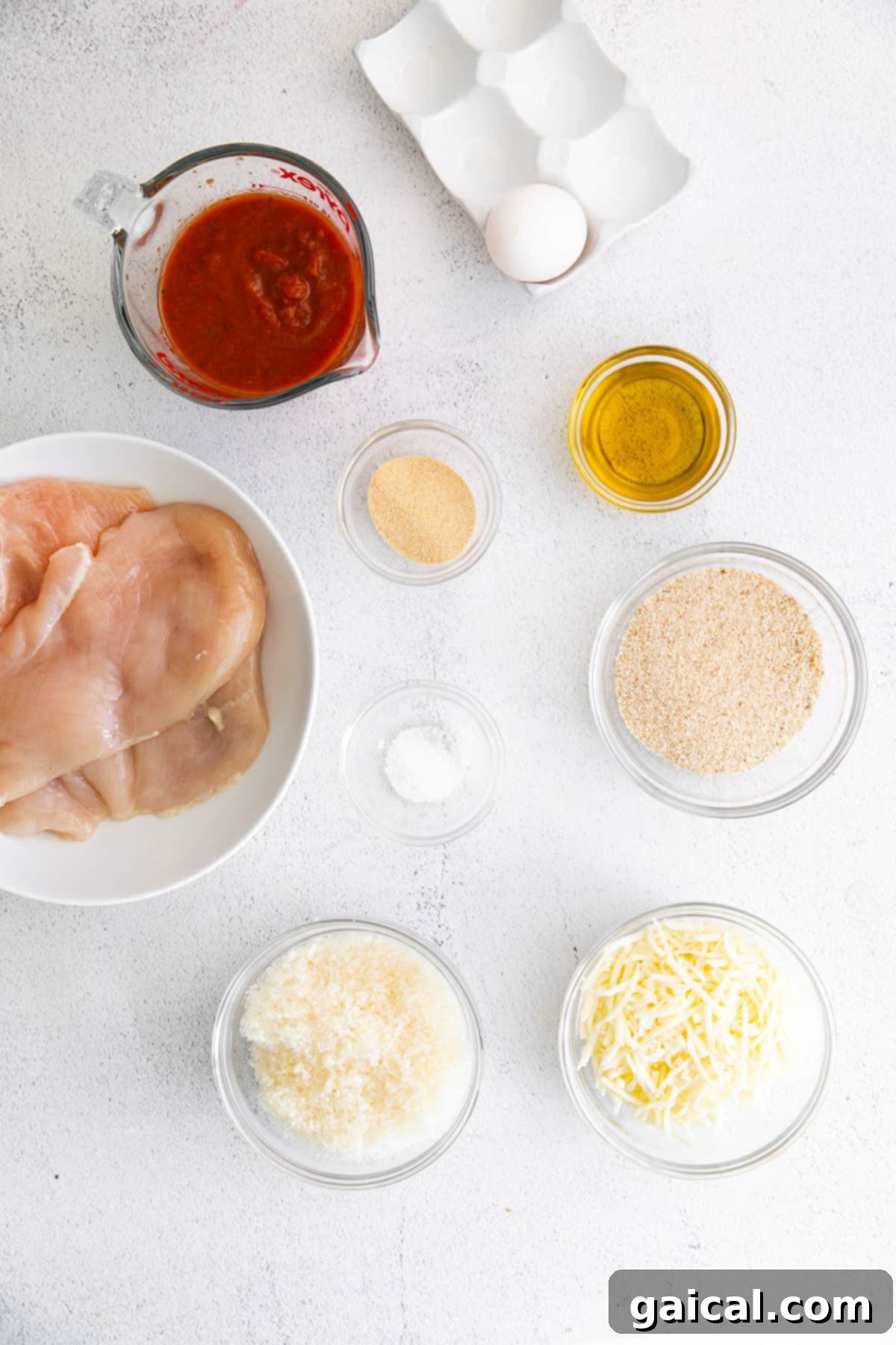 Fresh ingredients for baked chicken parmesan laid out on a kitchen countertop.