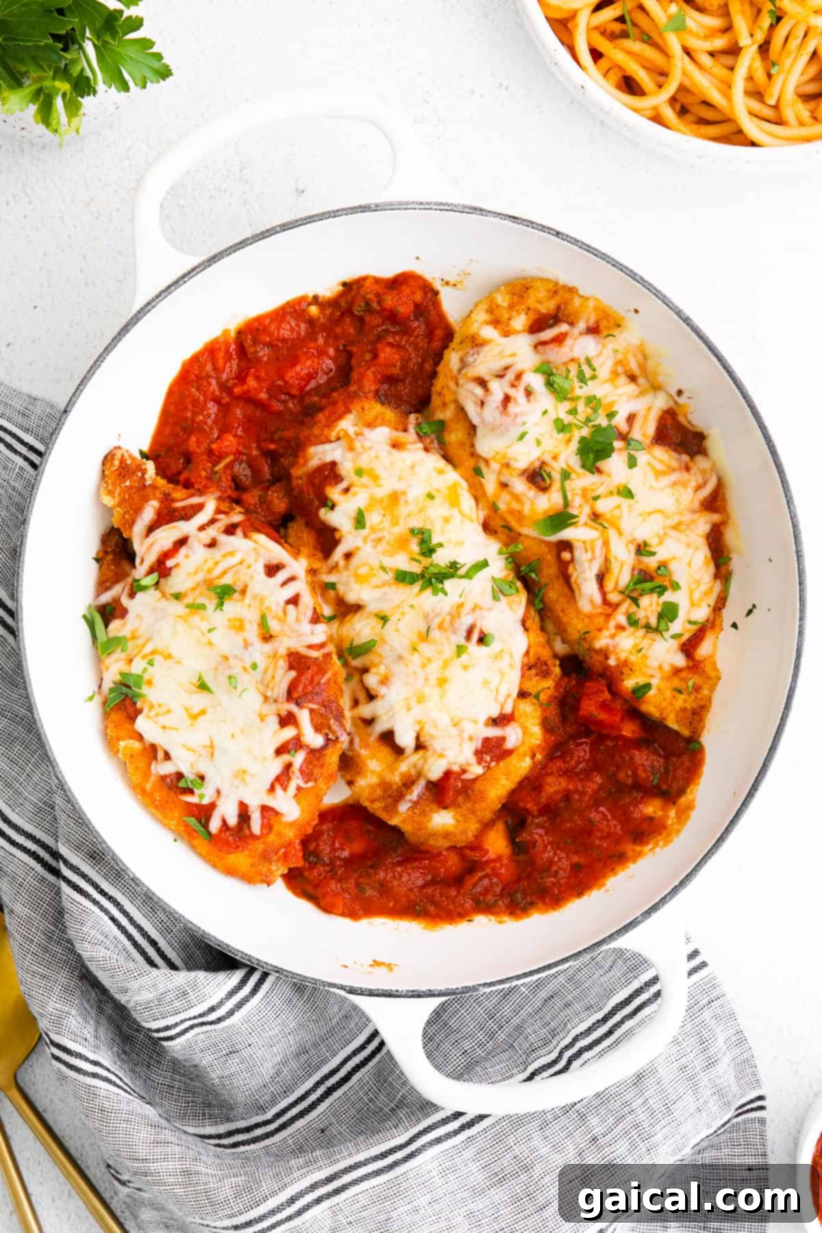 Baked chicken parmesan in a casserole dish, bubbling with cheese and sauce.