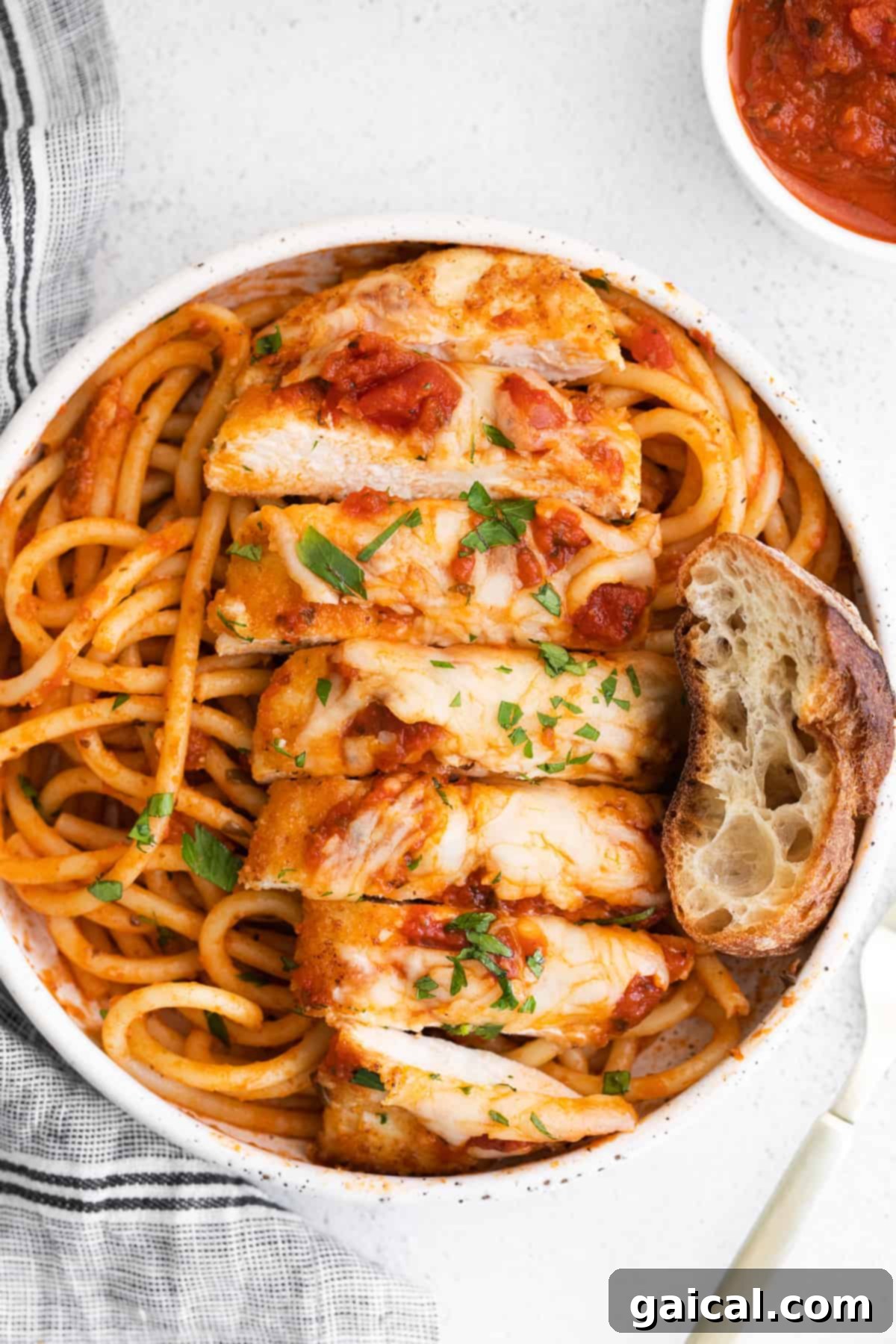 Sliced chicken parmesan served on top of noodles, ready to be eaten.