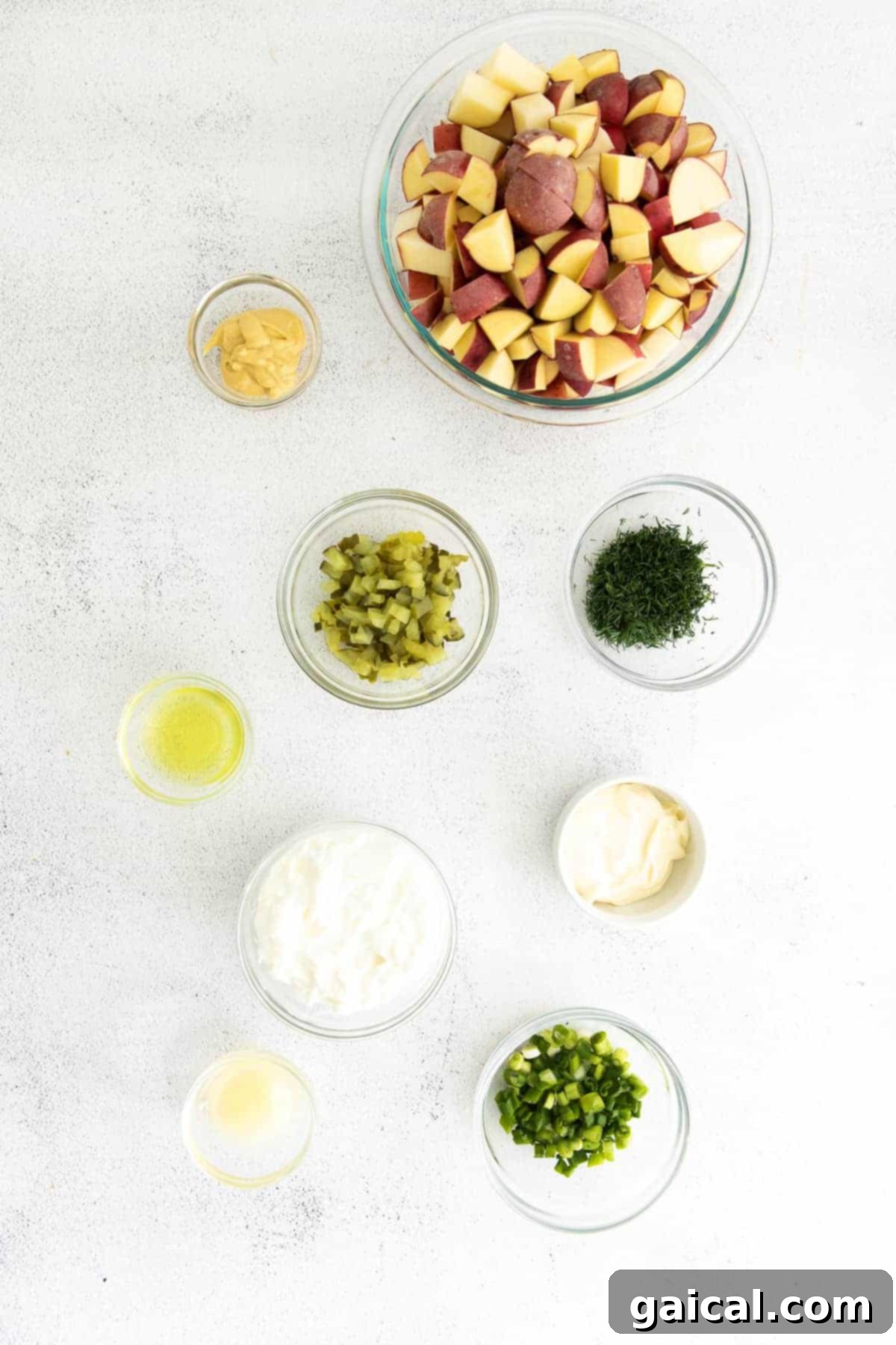 All the fresh ingredients for red potato salad laid out in small bowls, ready for preparation.