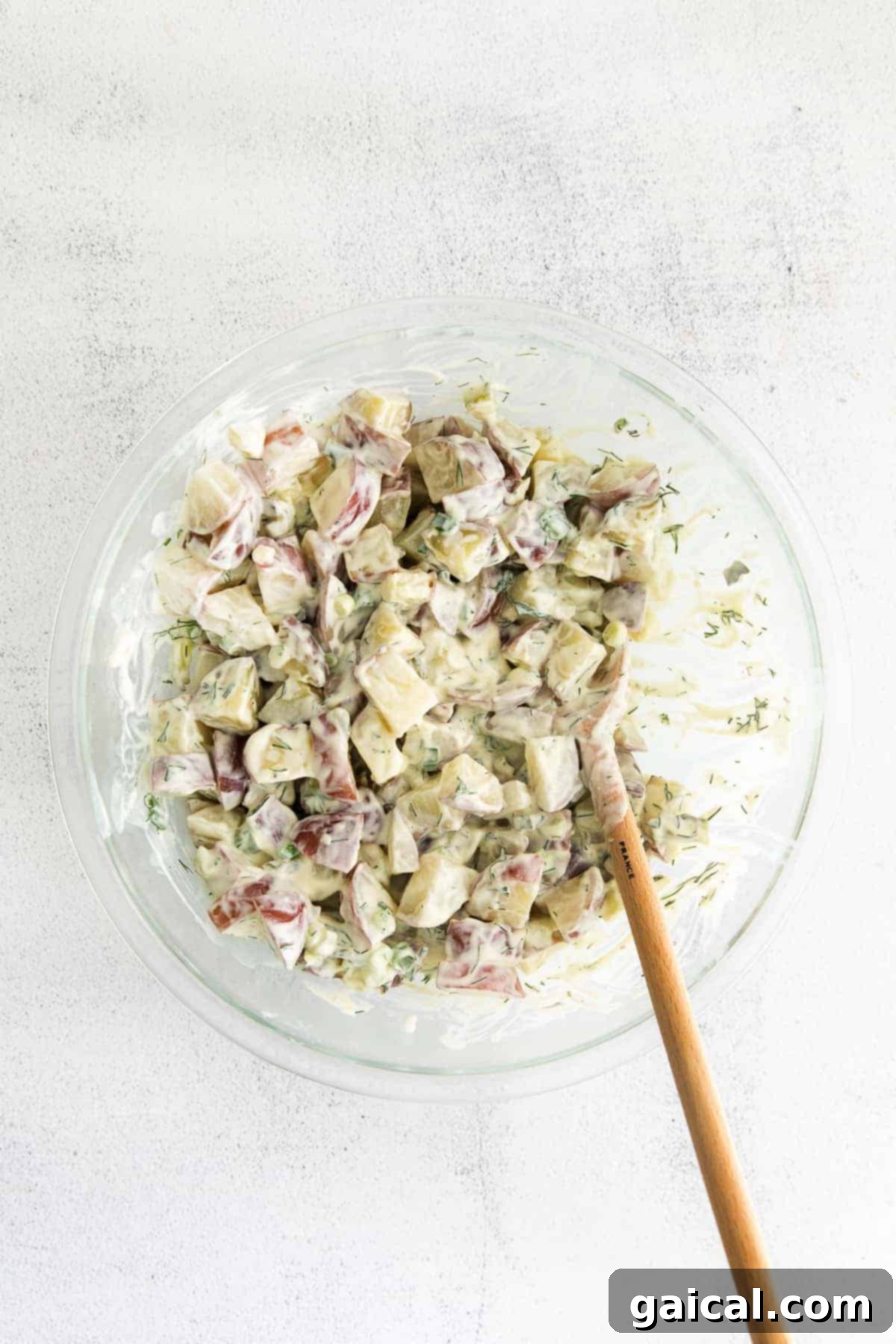 A rustic bowl filled with generous portions of creamy red potato salad.