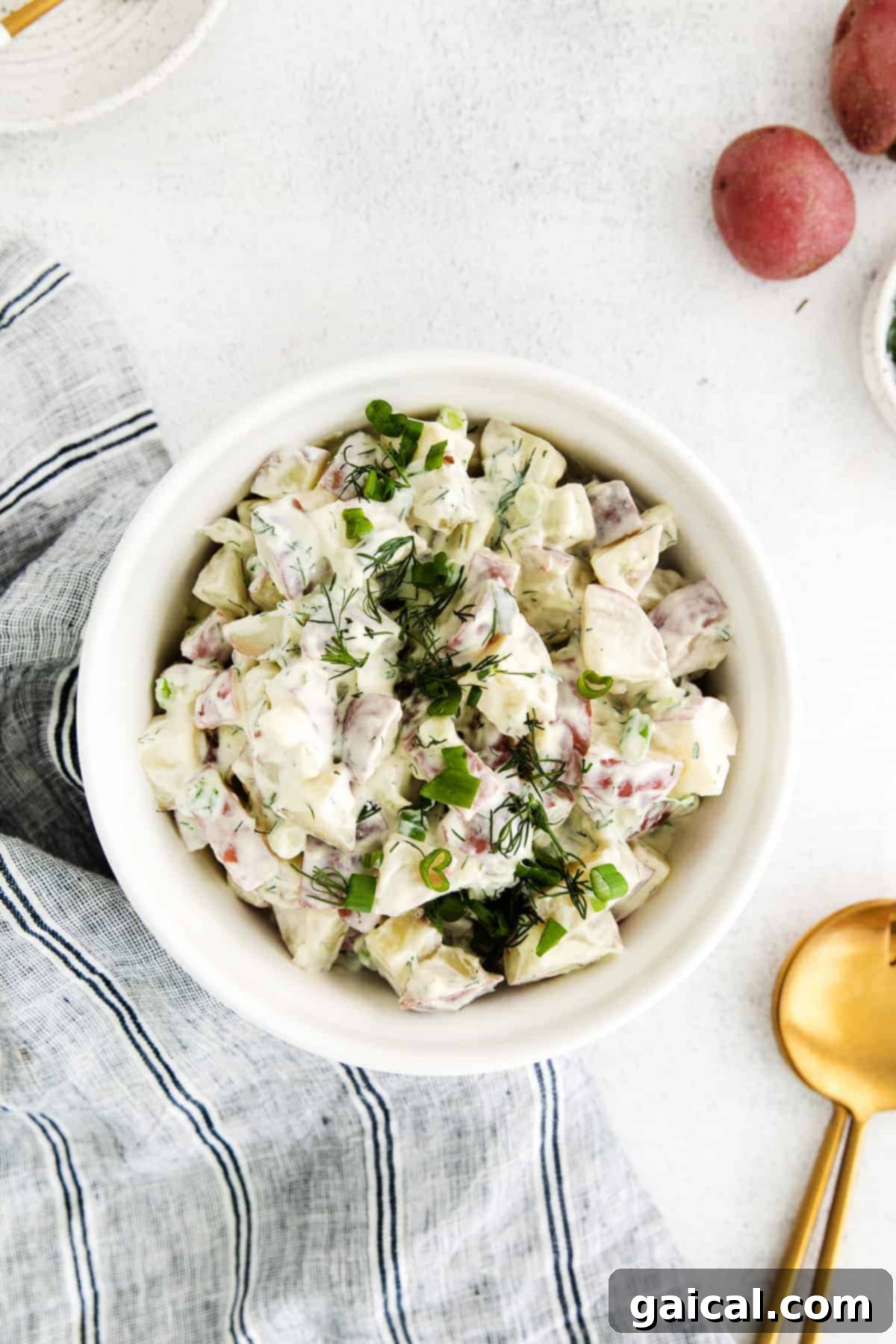 A close-up shot of red potato salad, highlighting its creamy texture and fresh dill garnish.