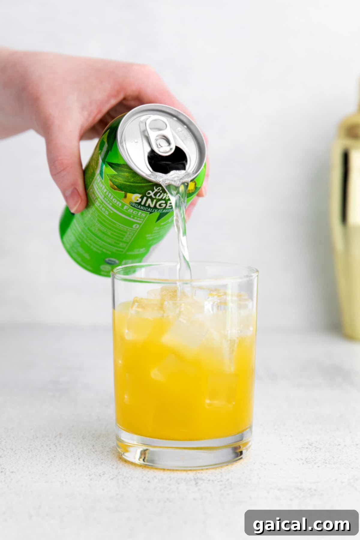 Adding the finishing touch of sparkling water to a refreshing virgin margarita. Pouring sparkling water into a glass with a virgin margarita mixture over ice.