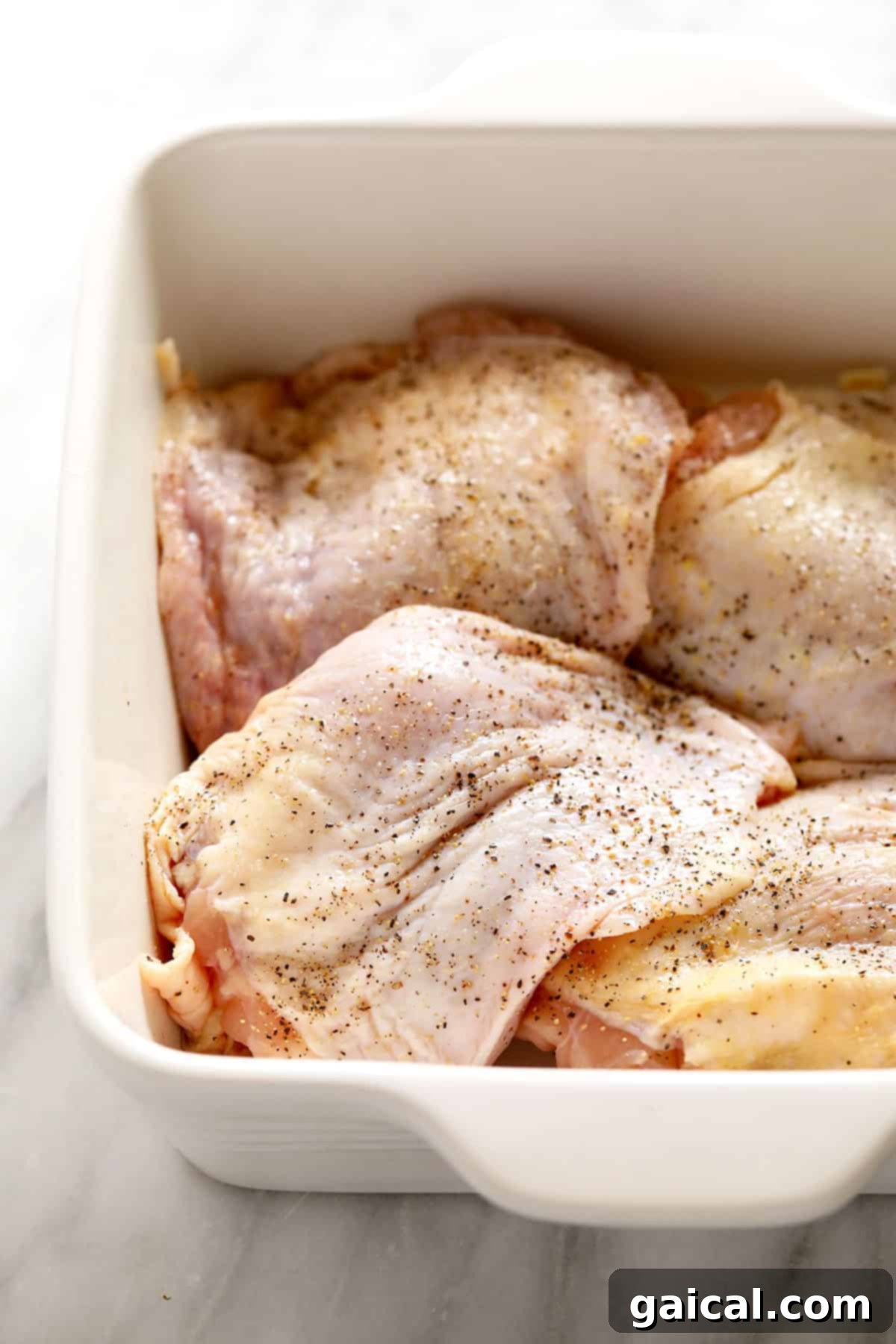 Perfectly Smoked Chicken Thighs 3 Chicken thighs marinating in a casserole dish before smoking.