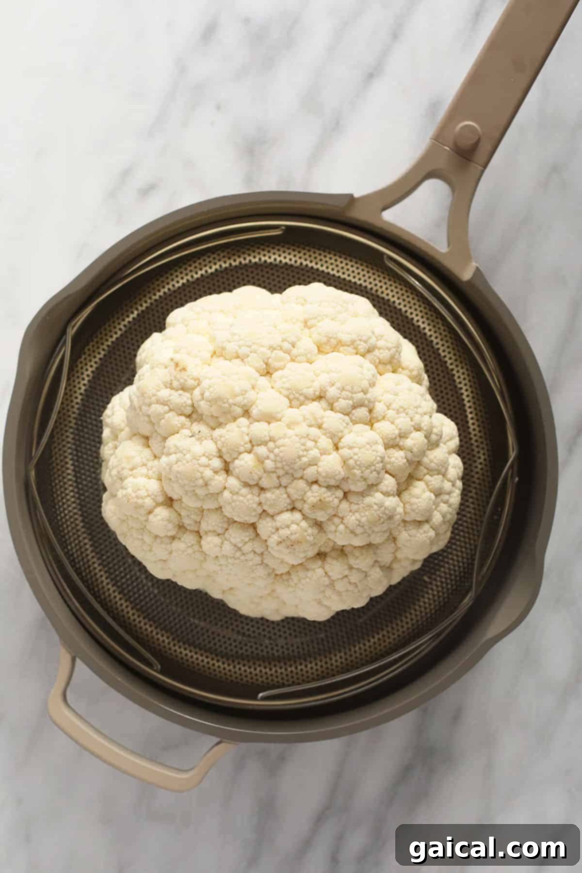 Fire-Kissed Cauliflower 3 A fresh head of cauliflower resting in a steamer basket, ready for the initial cooking phase.
