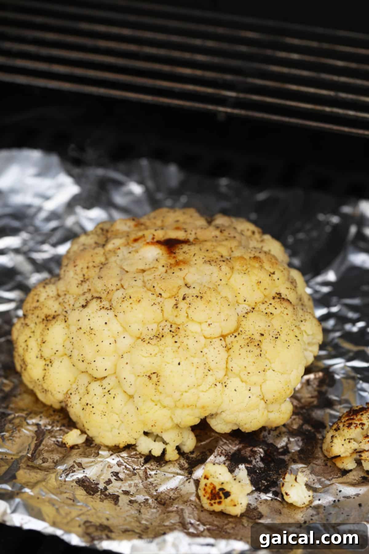 Fire-Kissed Cauliflower 4 A vibrant whole head of cauliflower, seasoned and placed directly on the grill grates, ready to achieve a perfect char.