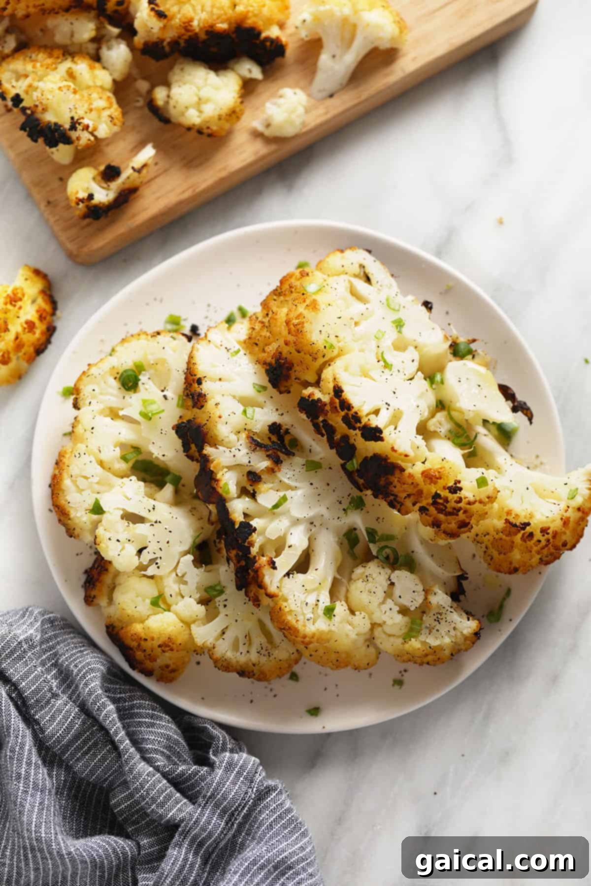 Fire-Kissed Cauliflower 6 A beautifully arranged plate of grilled cauliflower steaks, garnished with fresh herbs, showcasing their golden-brown edges.