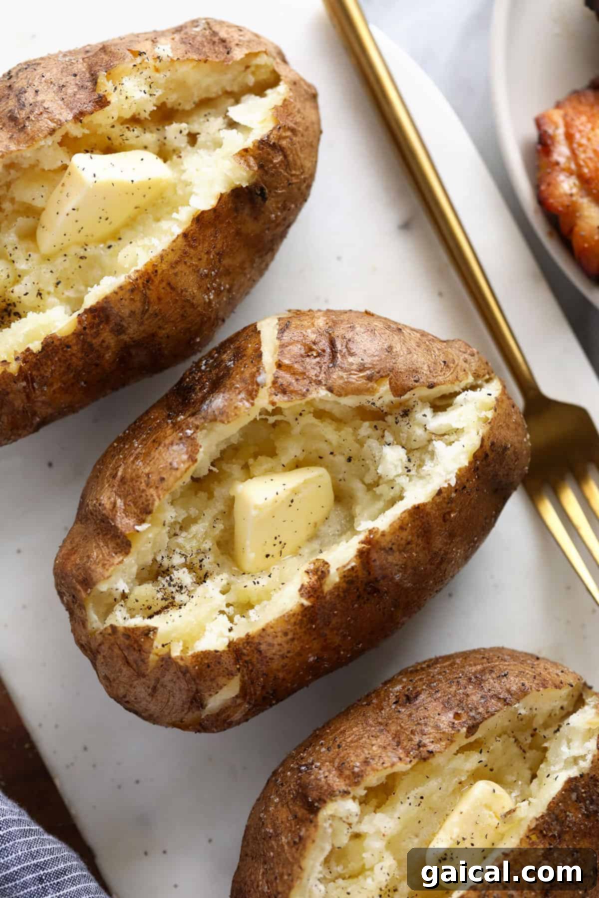 Super simple smoked baked potatoes that'll give you fork tender baked potatoes every time. baked potatoes with cutting board and butter