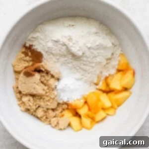 Sun-Kissed Peach Muffins 3 Dry ingredients and peach chunks mixed in a white bowl for peach muffins.
