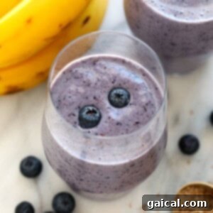 Your Guide to Freezing Blueberries 4 A vibrant purple blueberry banana smoothie in a glass, garnished with fresh blueberries.
