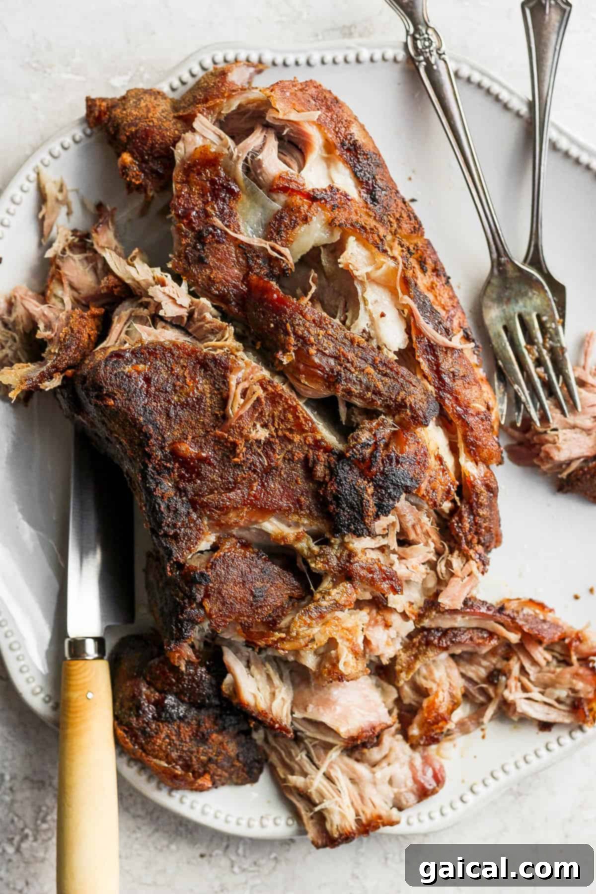 Shredded slow roasted pork shoulder piled high on a platter, ready to serve, showcasing crispy edges.