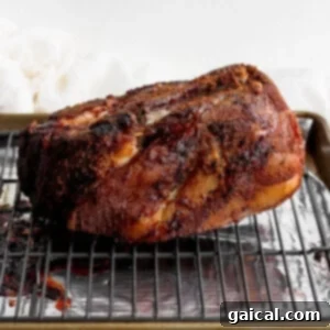 A BBQ pork roast resting on a baking sheet with a wire rack after being seared.