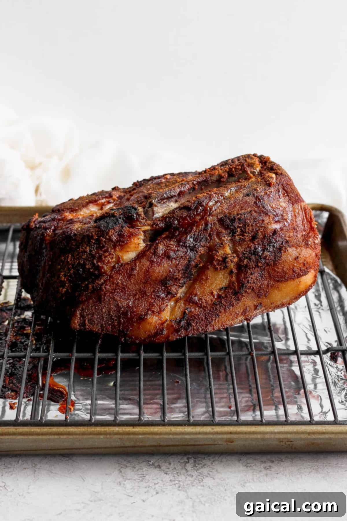 Crispy, golden-brown slow cooked pork shoulder resting on a wire rack after roasting, ready for the resting period and shredding.
