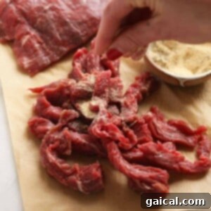 A person slicing beef on a cutting board for beef stroganoff.