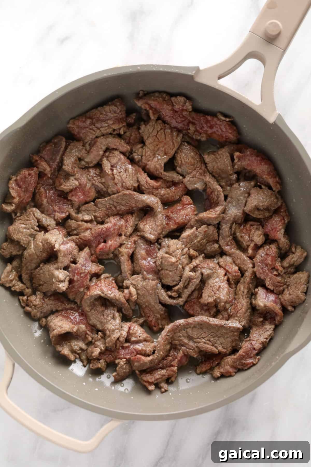 Simple Weeknight Beef Stroganoff 4 Thinly sliced beef strips in a hot skillet, ready for searing.