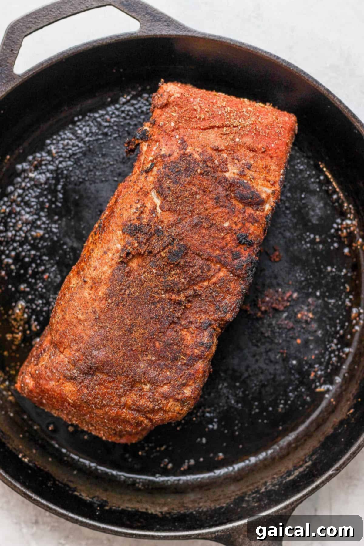 Pork shoulder being seared in a cast iron. 