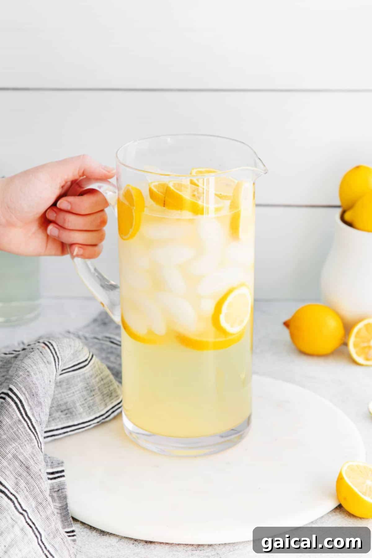 A pitcher of homemade lemonade filled with ice and fresh lemon slices, ready to be poured.