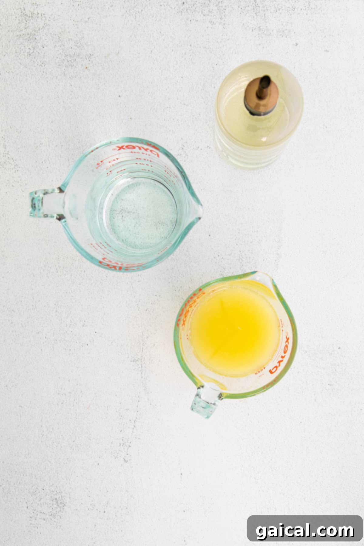 Close-up of fresh lemon juice, simple syrup, and water being combined on a kitchen counter, highlighting the simple ingredients.