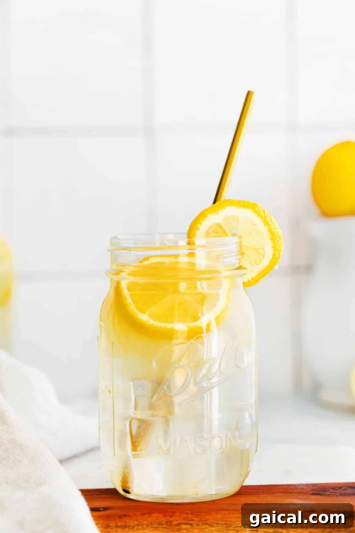 A mason jar filled with perfectly golden homemade lemonade, garnished with a lemon slice, sitting on a wooden surface.