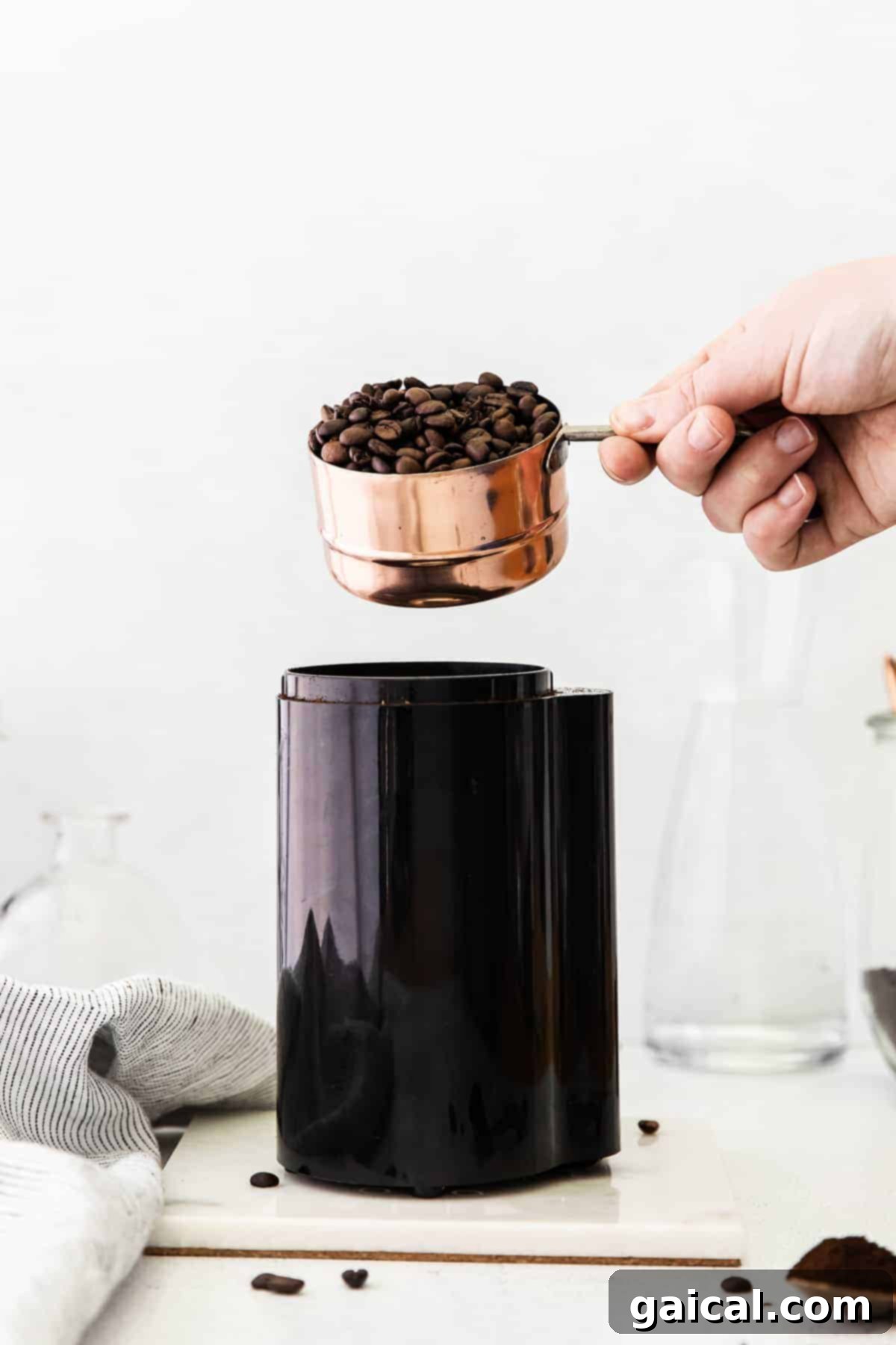 Crafting the Perfect Cold Brew 4 Pouring coffee beans into a coffee grinder.