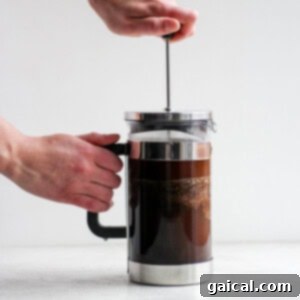 Crafting the Perfect Cold Brew 8 A person making coffee with a French press.