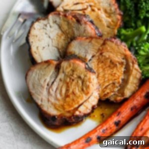 Perfectly sliced pork tenderloin on a plate, served with vibrant broccoli and tender carrots, showcasing a complete meal.