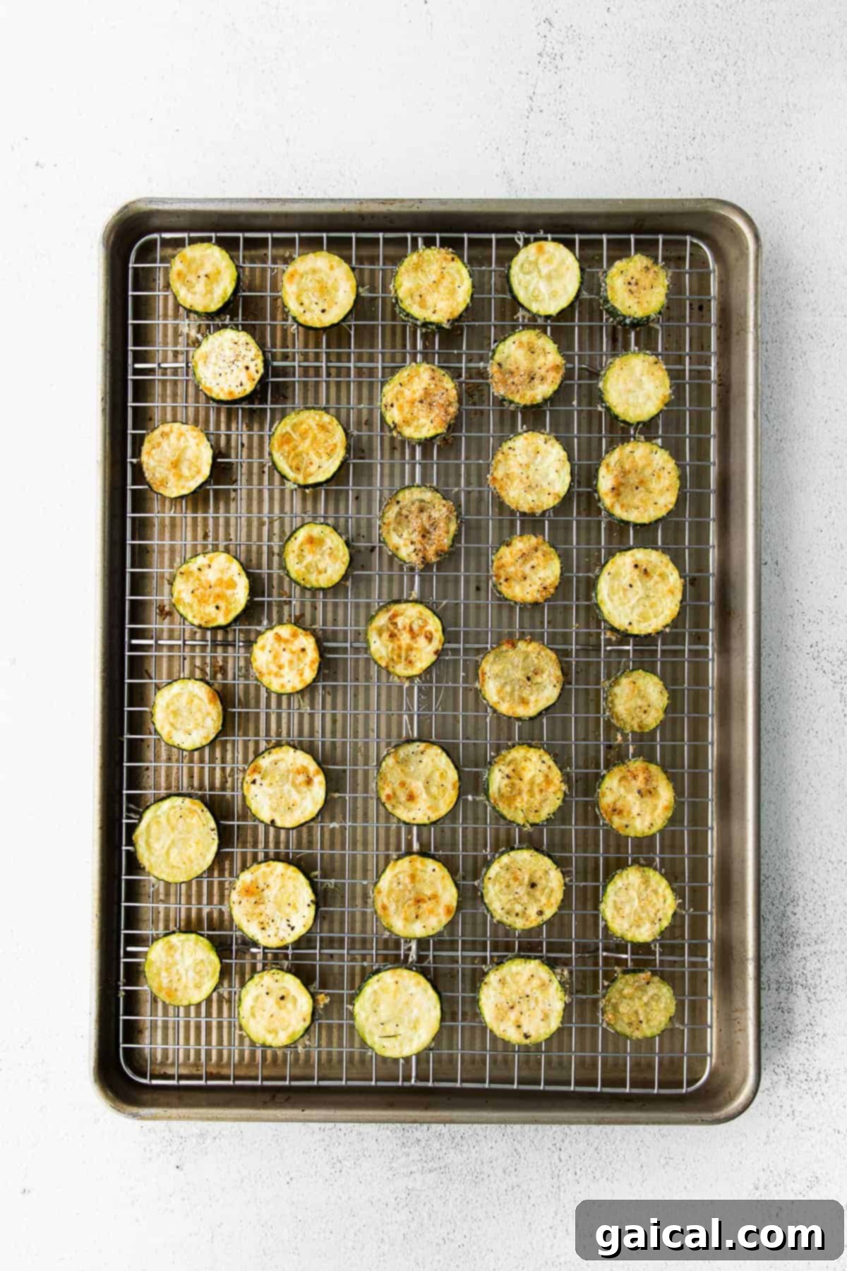 Crispy Parmesan Zucchini Bites 4 A close-up of perfectly golden, crispy Parmesan baked zucchini arranged neatly on a parchment-lined baking sheet, fresh out of the oven, highlighting their irresistible texture.