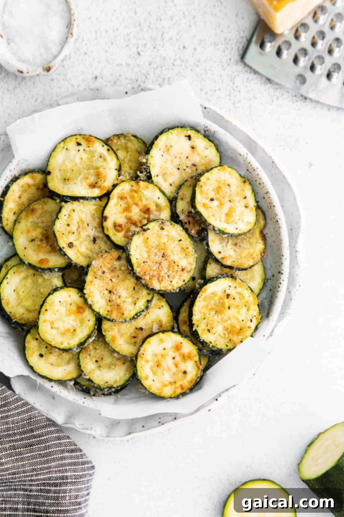 Crispy Parmesan Zucchini Bites 5 A close-up shot of freshly sliced zucchini rounds meticulously coated in a rich mixture of finely grated Parmesan cheese, fragrant salt, savory black pepper, and aromatic garlic, arranged on a surface and eagerly awaiting their journey to the oven for baking.