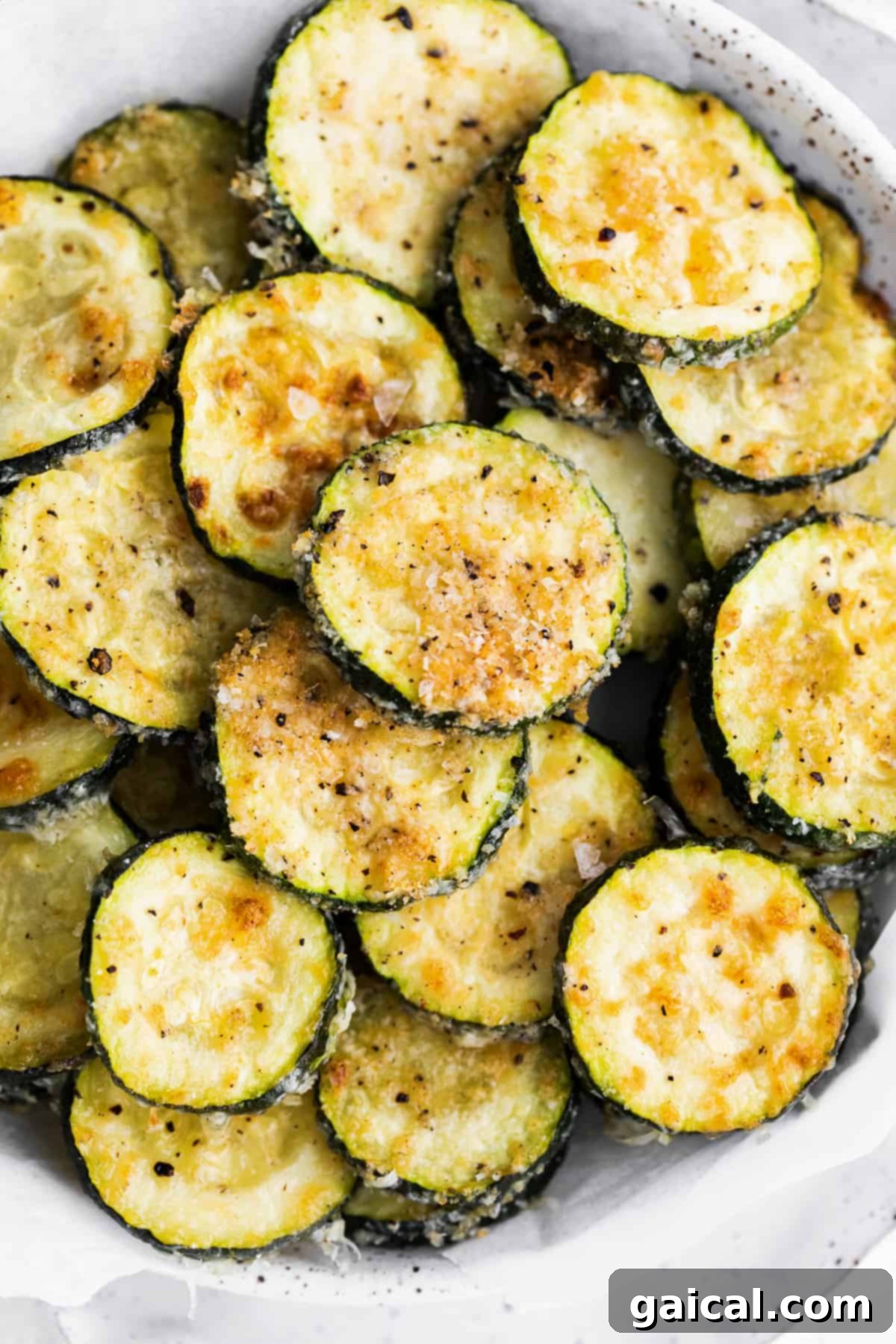 Crispy Parmesan Zucchini Bites 6 A vibrant and inviting bowl of perfectly baked zucchini, coated in Parmesan and spices, presented beautifully as a healthy and flavorful meal or snack option. The zucchini coins are golden and appear delightfully crisp.
