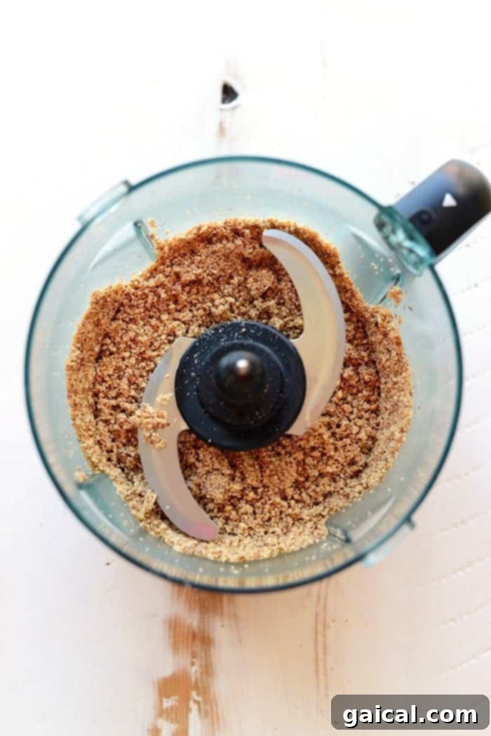A food processor blending ingredients for homemade cherry pie energy balls, showing a rich, dough-like consistency.