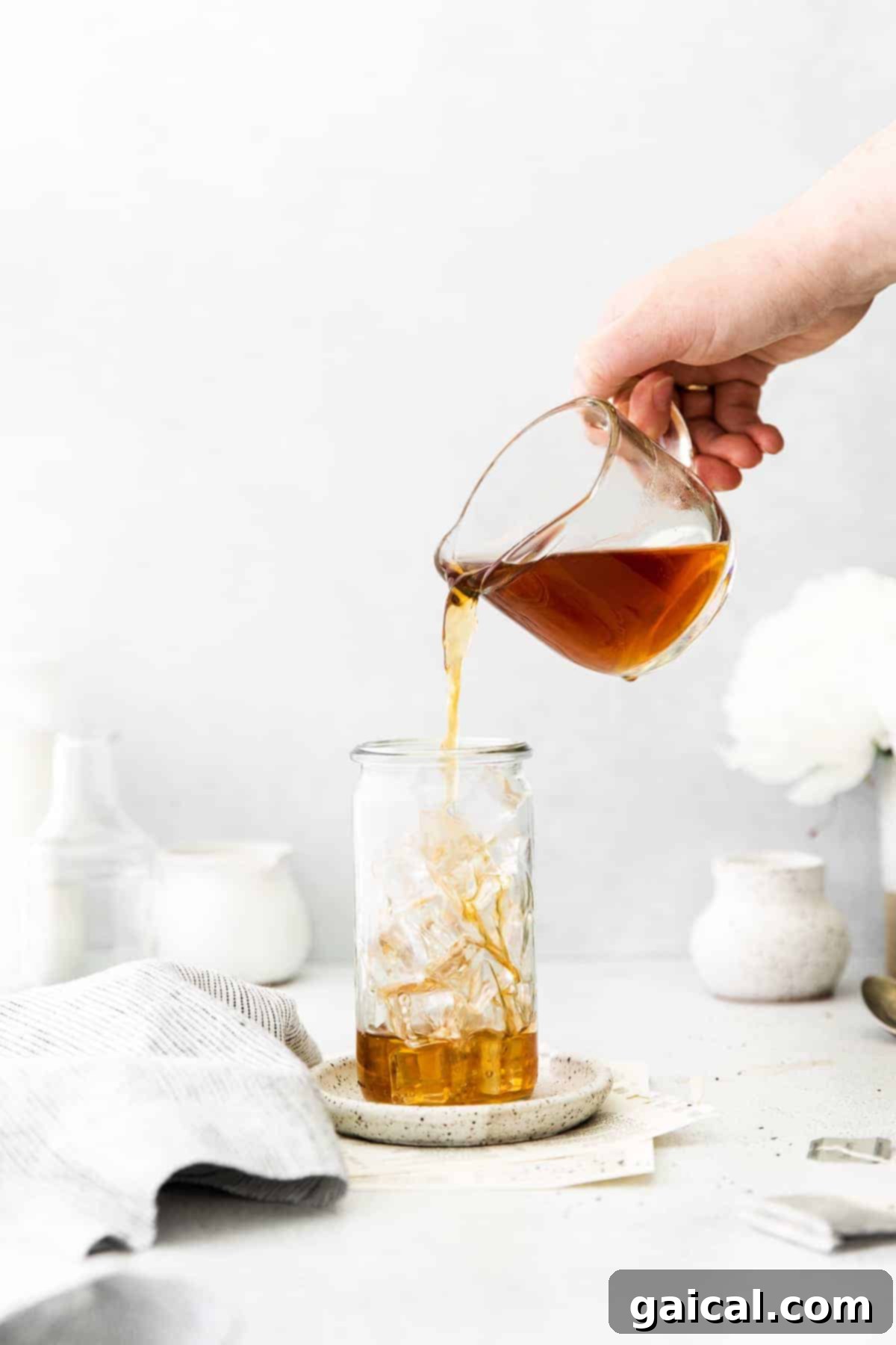 First Step: Pouring Tea over Ice for Your Iced London Fog Pouring freshly brewed Earl Grey tea into a glass filled with ice.